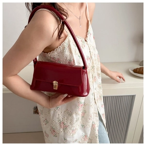 Detail of burgundy baguette bag with gold push-lock closure and glossy patent finish