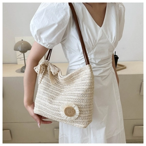 Detail of straw tote bag featuring a woven sunflower and beige lace bow accessory