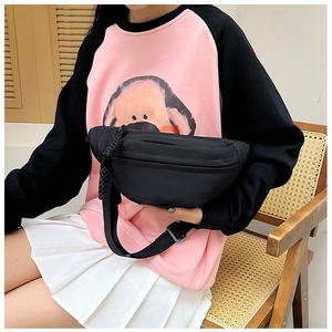 Detail of a minimalist black nylon waist bag with rope zipper decor on a casual outfit