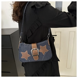 Detail of dark blue denim shoulder bag with brown leather stars and silver metal buckle
