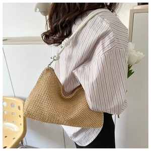 Detail of handwoven straw tote bag with a white knotted shoulder strap on a model