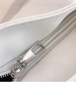 Detailed macro shot of silver smooth metal zipper pull on off-white leather tote bag