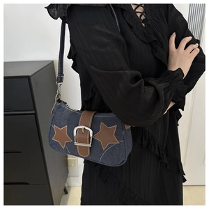 Detailed view of blue denim shoulder bag with brown leather stars and metallic buckle strap