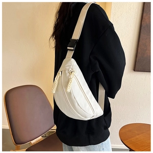 Detailed back view of a beige crossbody fanny pack shown on model in minimalist interior