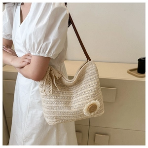 Detailed view of beige straw tote bag featuring lace bow and sunflower accent decoration
