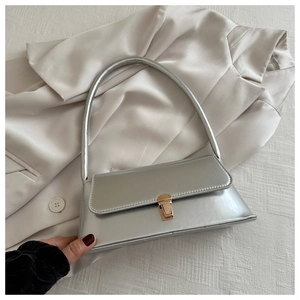 Detailed shot of silver faux leather shoulder bag with gold clasp on champagne satin