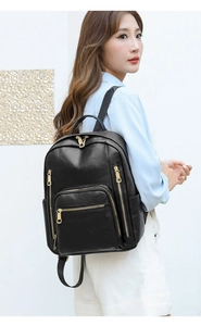 Close-up of a stylish black PU leather backpack with gold zippers shown on a model's back