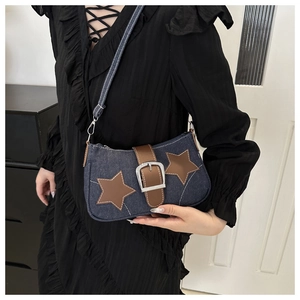 Detail of blue denim shoulder bag with brown star patches and silver metal buckle