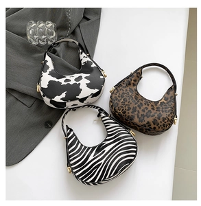 Close-up of crescent bags with cow, leopard, and zebra prints on a styled background
