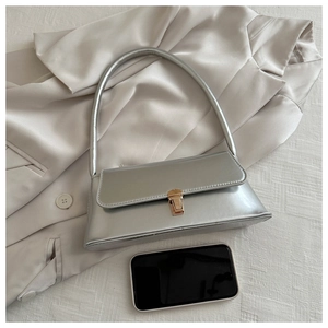 Detailed view of silver metallic underarm bag with gold buckle on silk fabric background