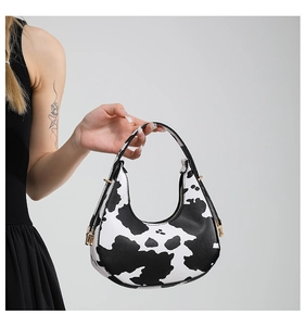 Detail of a zebra print half-moon bag featuring a gold zipper and premium PU texture