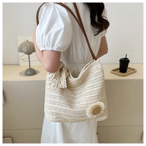 Detail view of woven sunflower straw tote bag with delicate lace bow and leather straps
