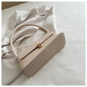 Detail of cream patent leather underarm bag with elegant square gold metal clasp