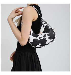 Side view of woman wearing a stylish black and white cow print hobo shoulder bag