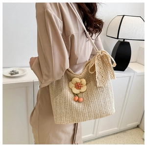 Straw tote bag detail with lace bow and sunflower pendant in a warm lifestyle setting