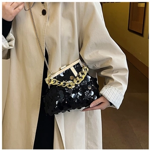 Close-up of black sequined crossbody bag with gold chain strap on a trench coat