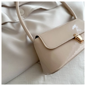 Detail of beige patent leather shoulder bag with gold metal buckle on silk fabric