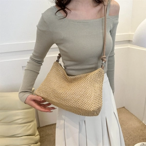Minimalist straw woven crescent tote bag with leather strap shown on a model
