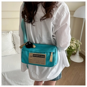Detailweergave van een turquoise nylon schoudertas met verstelbare riem op de rug