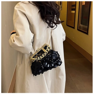 Detailed view of black sequin evening bag with gold chain and metal frame closure