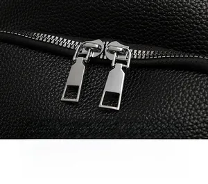 Detailed macro shot of smooth dual silver zippers on black lychee grain leather bag