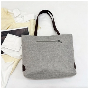 Detailed view of grey linen tote bag featuring a practical rear zipper pocket for storage