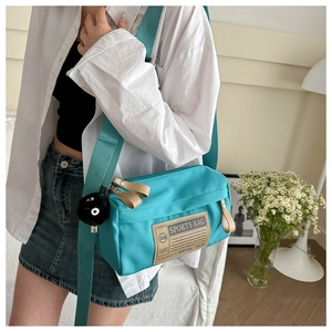 Detail van blauwe nylon crossbodytas met ritssluiting en een schattige pluche monster hanger