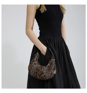 Detailed view of leopard print hobo bag with gold buckle on a black sleeveless dress