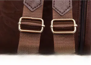 Detail of adjustable brown nylon shoulder strap with gold buckle on leather backpack