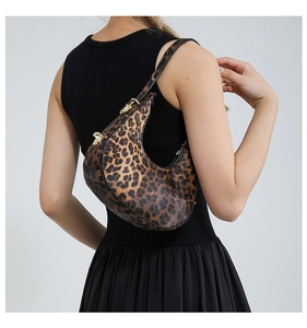 Detail view of leopard print crescent bag with gold metal buckle on a shoulder strap