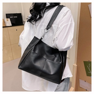 Detail view of black PU leather tote bag featuring stylish silver metal rings and short chains