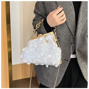 Detailed view of a white sequined clutch bag with gold chain strap held by a model