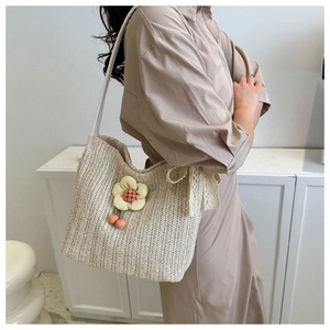 Detail of woven straw tote bag with 3D yellow floral charm and orange beads trim