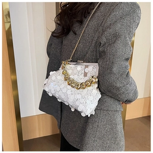 Detailed view of white sequin frame bag with gold double chains on a grey blazer suit