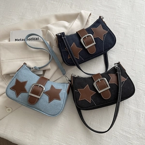 Denim underarm bag with star patches and chain decoration in light blue and black colors