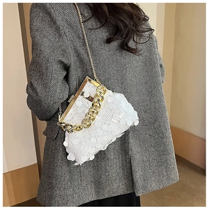 Detail of white sequined handbag with gold chain strap on a grey blazer outfit
