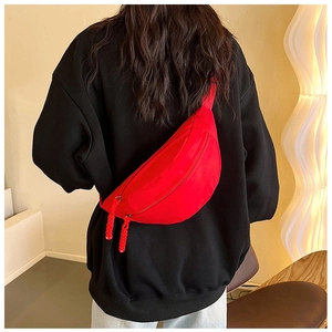 Rear view of a model wearing a bright red crescent waist bag with adjustable strap