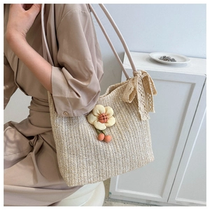 Detail of hand-woven straw tote bag with sunflower pendant and lace bow accessory