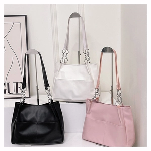 Minimalist faux leather tote bag detail with metal chain strap and dual front pockets