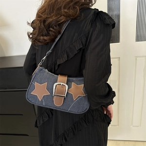 Denim shoulder bag with leather stars and chain detail worn by a model in casual style