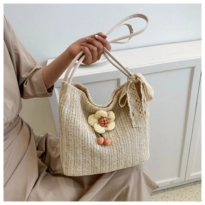 Detailed close-up of straw tote bag with lace bow and floral charm accessory
