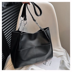 Detailed view of black tote bag with silver chain strap and front pocket texture