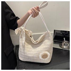 Detail of straw tote bag with white lace bow and woven sunflower accent in a lifestyle setting