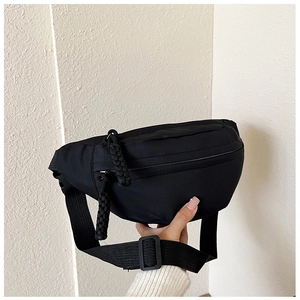 Detail of minimalist black nylon waist bag featuring dual zippers and adjustable strap