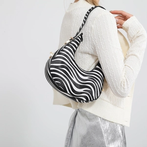 Zebra print crescent shoulder bag with gold hardware shown on model in minimalist setting
