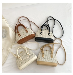 Detail view of woven straw shell bags with floral embroidery and vegan leather handles