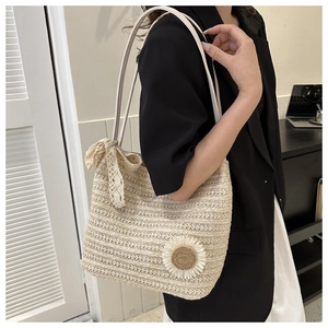 Detail of beige woven straw tote bag with 3D daisy flowers and a white lace bow accessory