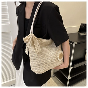 Detail of straw woven tote with lace bow and daisy flower on white shoulder bag