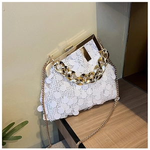 Detail of white sequin clutch bag featuring gold metal frame and chunky chain handle