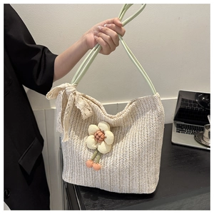 Detail of hand-woven straw tote with large fabric flower and lace bow on shoulder strap